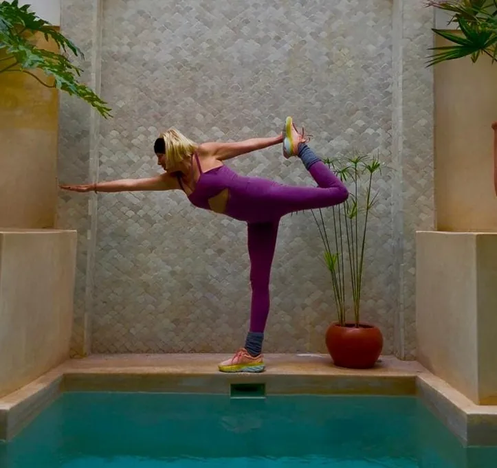 Maëlla, professeure de yoga, en posture du danseur au bord d’un bassin de riad à Marrakech